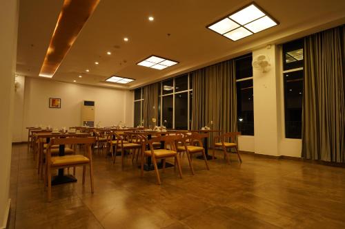 una sala da pranzo con tavoli, sedie e finestre di Tea Tree Suites,Manipal a Manipal