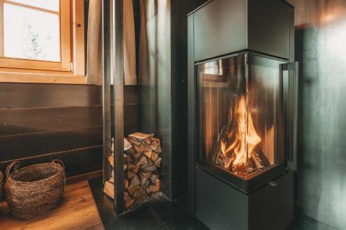 a wood stove in a room with a pile of wood at Hüttendorf Schlögelberger in Sankt Margarethen im Lungau