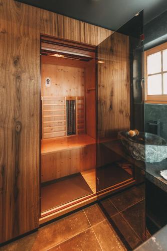 a walk in shower in a room with wooden walls at Hüttendorf Schlögelberger in Sankt Margarethen im Lungau