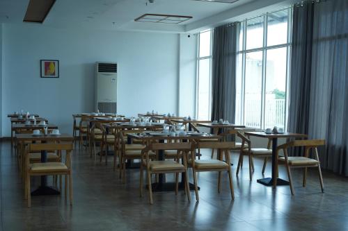 uma fila de mesas e cadeiras num quarto com janelas em Tea Tree Suites,Manipal em Manipal