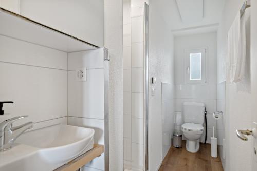 a white bathroom with a sink and a toilet at Erlen Rooms in Lucerne