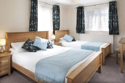 two beds in a room with windows and curtains at Gwithian Holidays in Hayle