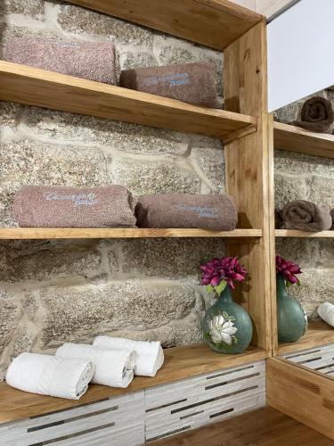 a bathroom with wooden shelves with towels at As Fontaiñas 