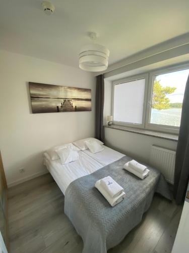 una camera da letto con un letto e due asciugamani di Apartamenty RÓŻA WIATRÓW - MARINA BORKI a Augustów