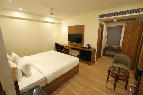 a hotel room with a bed and a desk and a television at Hotel Sharda Residency in Patna