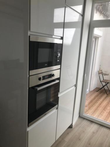 une cuisine blanche avec un four micro-ondes et une fenêtre dans l'établissement Joli appartement T3 rénové serviettes non incluses, à Sète