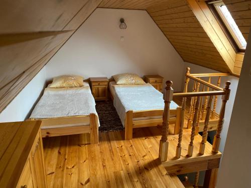 two beds in a attic room with a staircase at Mazurski Domek in Mikołajki