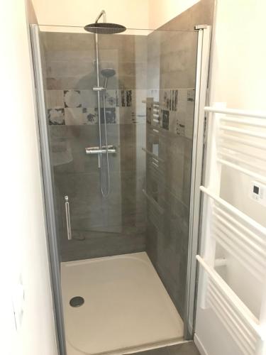 une douche avec une porte vitrée dans une salle de bain dans l'établissement Joli appartement T3 rénové serviettes non incluses, à Sète
