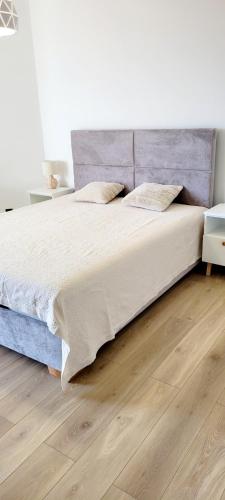 a large bed in a bedroom with a wooden floor at PINEA Apartments Pobierowo z niesamowitym widokiem na morze oraz jacuzzi w wybranych apartamentach in Pobierowo