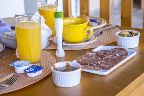 a wooden table with plates of food and orange juice at Pousada Sonho Meu in Camanducaia