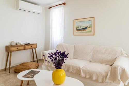 a living room with a white couch and a yellow vase on a table at Anemologio 301 Tinos in Agios Ioannis Tinos