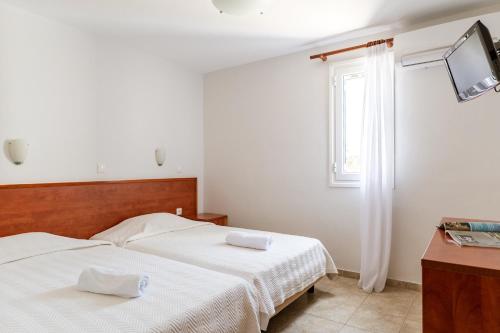 a bedroom with two beds and a tv on the wall at Anemologio 301 Tinos in Agios Ioannis Tinos