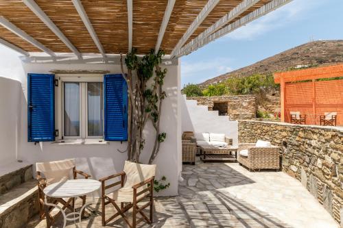 a patio with blue shutters and a table and chairs at Anemologio 301 Tinos in Agios Ioannis Tinos