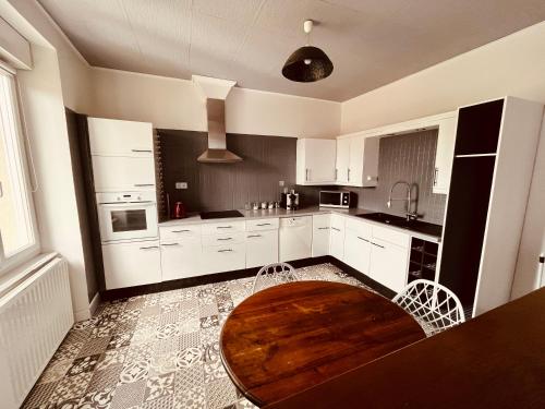 une cuisine avec des placards blancs et une table en bois dans l'établissement Au Bonheur Arédien, à Saint-Yrieix-la-Perche