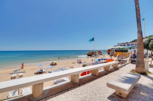 a beach with chairs and people on the sand and the ocean at Albufeira Valley 2 With Pool by Homing in Albufeira