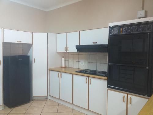 a kitchen with white cabinets and a black appliance at Africa Dawn Guesthouse in Musina