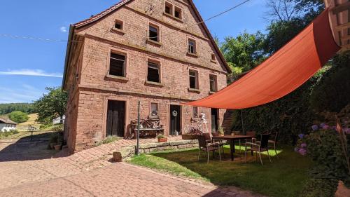 ein altes Backsteingebäude mit einem Tisch davor in der Unterkunft Hof Helmenhube 2 in Gammelsbach