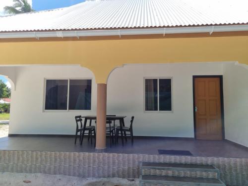 a small white house with a table and chairs at Le Nid de Bea Self-catering Apartments in La Digue