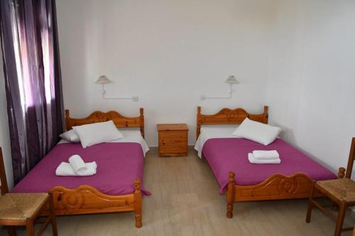 two beds in a room with purple sheets at PERDIKI STUDIOS in Kókkinon Nerón