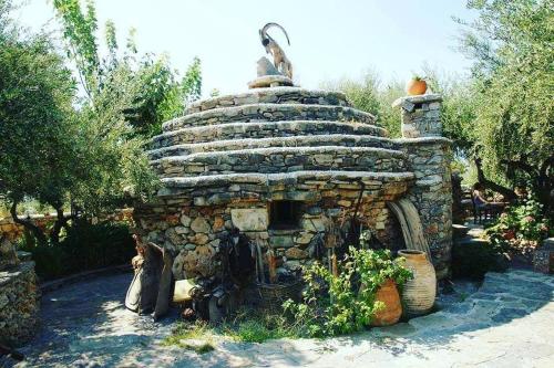 a stone oven in a garden with a person sitting next to it at Koumos in Kalyves
