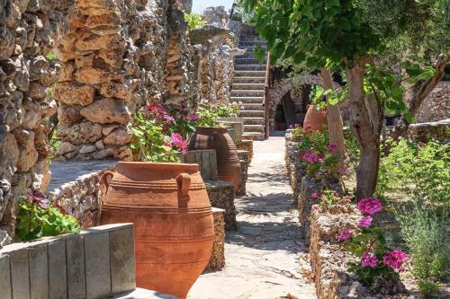 un jardín con flores y una pared de piedra en Koumos en Kalyves