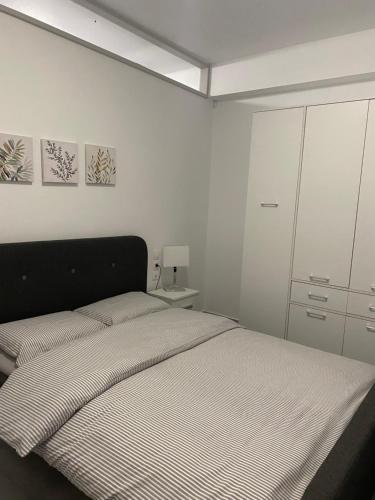 a white bedroom with a bed and a cabinet at Olympia's Guest House in Volos