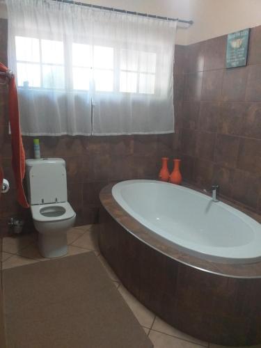 a bathroom with a large tub and a toilet at Africa Dawn Guesthouse in Musina