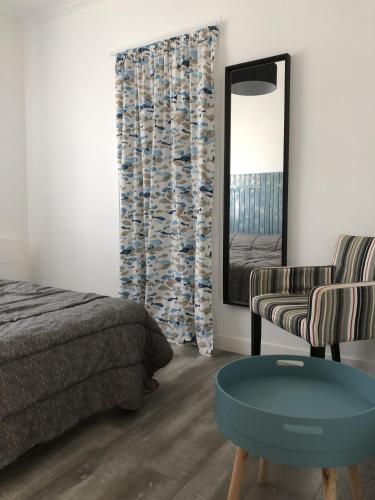 une chambre avec un lit, un miroir et une chaise dans l'établissement Vacances en famille a Oleron, au Château-dʼOléron