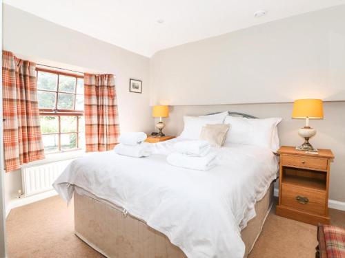 a bedroom with a bed with white sheets and pillows at Clover Cottage - Delightful 1-bed cottage in the heart of Ambleside in Ambleside