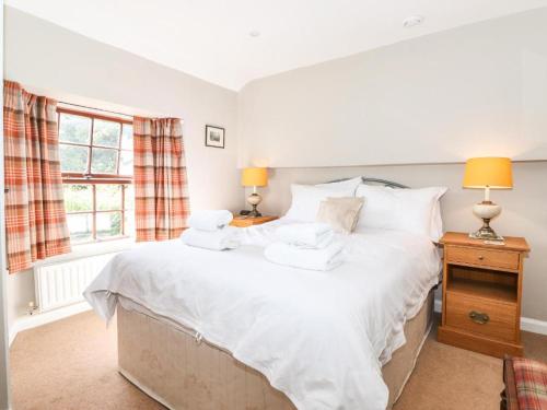 una camera da letto con un letto con lenzuola e cuscini bianchi di Clover Cottage - Delightful 1-bed cottage in the heart of Ambleside ad Ambleside