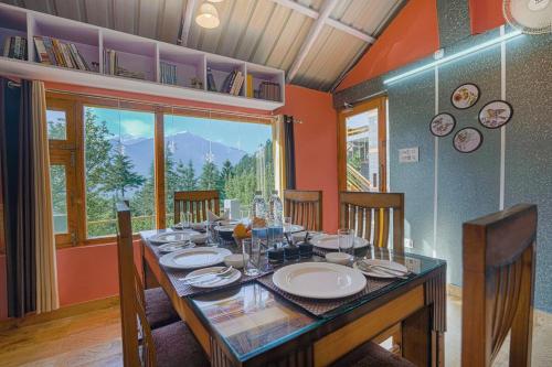 a dining room with a table and a large window at SaffronStays Kesar Villa, Manali - beautiful villa amidst an apple orchard - All clear roads in Manāli