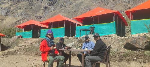 un grupo de personas sentadas en una mesa frente a un edificio en Buddy Hikers Stay Badrinath en Badrīnāth