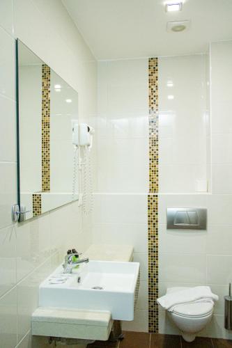 a white bathroom with a sink and a toilet at Hotel Rodon in Paralia Katerinis