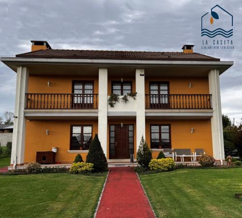 uma grande casa amarela com uma entrada vermelha em La Casita Villa Vacacional em Anero