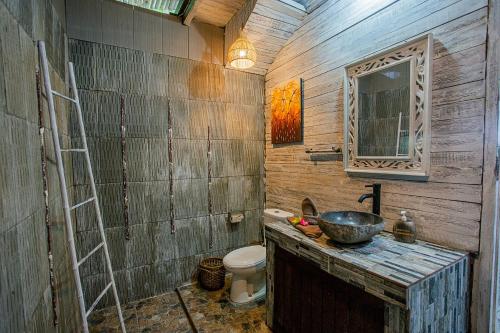 a wooden bathroom with a sink and a toilet at Naturale Villas in Nusa Lembongan