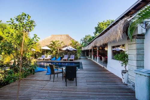 een houten loopbrug naast een resort met een zwembad bij Naturale Villas in Nusa Lembongan