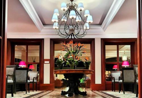 a lobby with a chandelier and a table with flowers at Fairmont Mount Kenya Safari Club in Nanyuki
