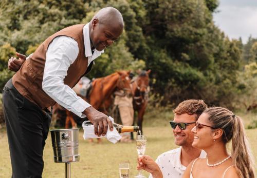 a man pouring a glass of wine for a woman at Fairmont Mount Kenya Safari Club in Nanyuki