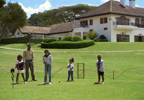 a group of people standing in a yard playing with nets at Fairmont Mount Kenya Safari Club in Nanyuki