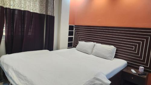 a bedroom with a white bed with an orange wall at Dream Palace Resort in Cox's Bazar