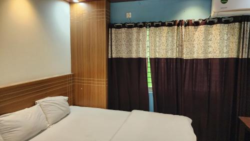 a bedroom with a bed and a window with curtains at Dream Palace Resort in Cox's Bazar