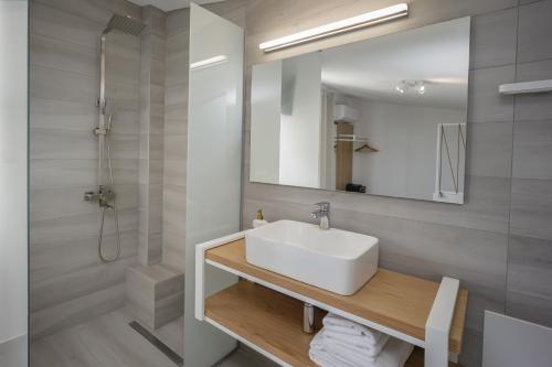 een badkamer met een witte wastafel en een spiegel bij Hermagio Villa George by Estia in Malia