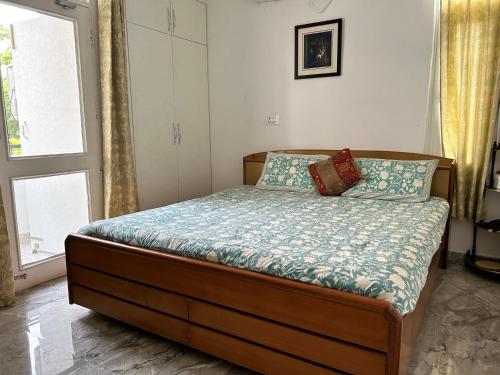 a bedroom with a bed with a blue comforter and a window at Cozy Nest - Garden Facing Apartment with Kitchen in Chandīgarh