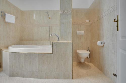 a bathroom with a tub and a toilet at Aphrodite Hotel Marianske Lazne in Mariánské Lázně