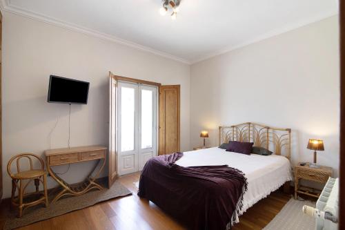 a bedroom with a bed and a tv on the wall at Casa da Cidade de Loulé in Loulé