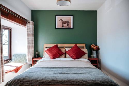 Dormitorio verde con cama con almohadas rojas en The Old Stable at Blackshaw Farm en Leek