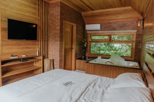 a bedroom with a bed and a tv and a window at Sonnen Schein Chalés in São Martinho