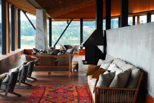 a living room with couches and tables and windows at Refugia Chiloé in San José