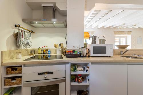 a kitchen with a counter with a sink and a microwave at Top Ático Plaza del Arenal - Gran terraza - Vistas - Solarium in Jerez de la Frontera