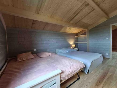 2 camas en una habitación con techo de madera en Le Gite des Genêts, en Coucouron